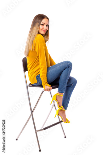 Beautiful young girl posing on a chair over white background.