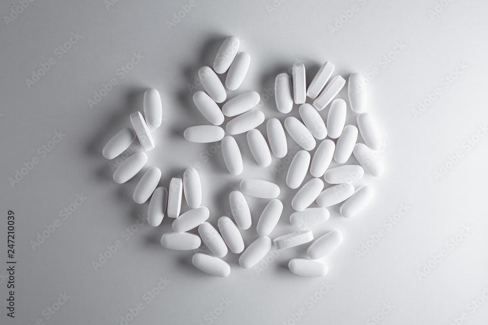 Heap of white pills on grey background Heap of white pills on grey background
