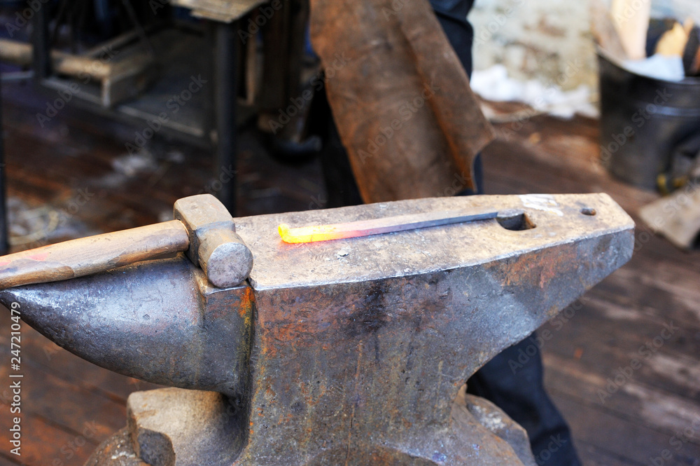 Blacksmith working metal with hammer on the anvil Blacksmith working metal with hammer on the anvil