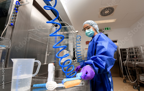 A young woman works in a hospital as a  medical hygiene worker. She is dressed  in special medical hygiene clothing and  carries out hygiene disinfecting and logistic tasks.