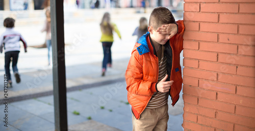 playing hide and seek. boy closed eyes his hands standing at brick wall