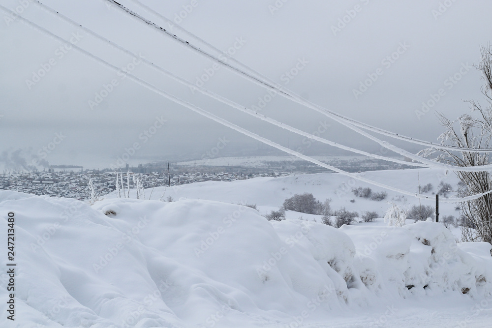 icy wires in the frost on the power line against the city winter sky icy wires in the frost on the power line against the city winter sky