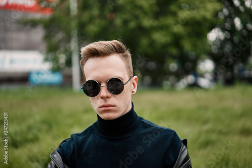 man in the hat wears sunglasses sitting on the grass