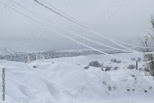 icy wires in the frost on the power line against the city winter sky