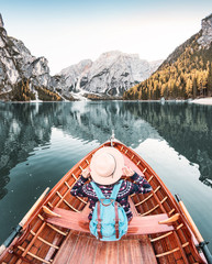 Happy asian woman sitting in wooden vintage boat floating and sailing on a Braies lake in Italian Alps mountains, Travel and dream vacation concept