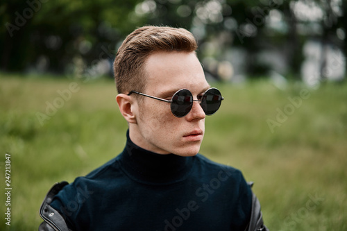 man in the hat wears sunglasses sitting on the grass
