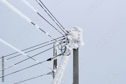 power line on a pole of many wires covered with a thick layer of snow