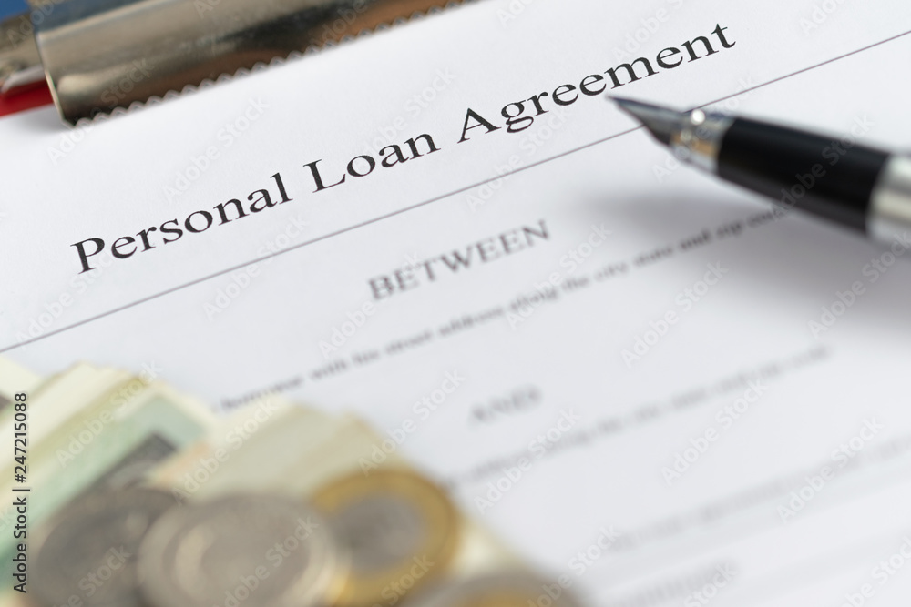 Personal loan agreement paper form with pen and money. Defocused business background. Personal loan agreement paper form with pen and money. Defocused business background.