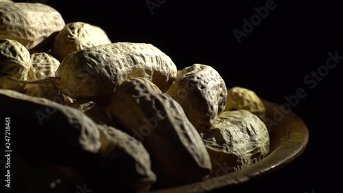 Raw Inshell Peanuts in Rotation. peanuts in shell. Snack closeup.   Peanuts in a bowl. Selective focus. black background. Studio shot. Healthy food concept.