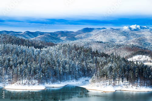Wonderful Croatian winter landscape, panorama of Lokvarsko lake and woods under snow in Gorski kotar and Risnjak mountain in background 