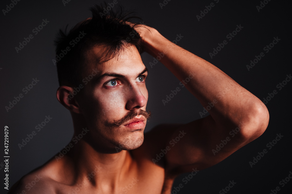 Young shirtless man with mustache thinking by the window