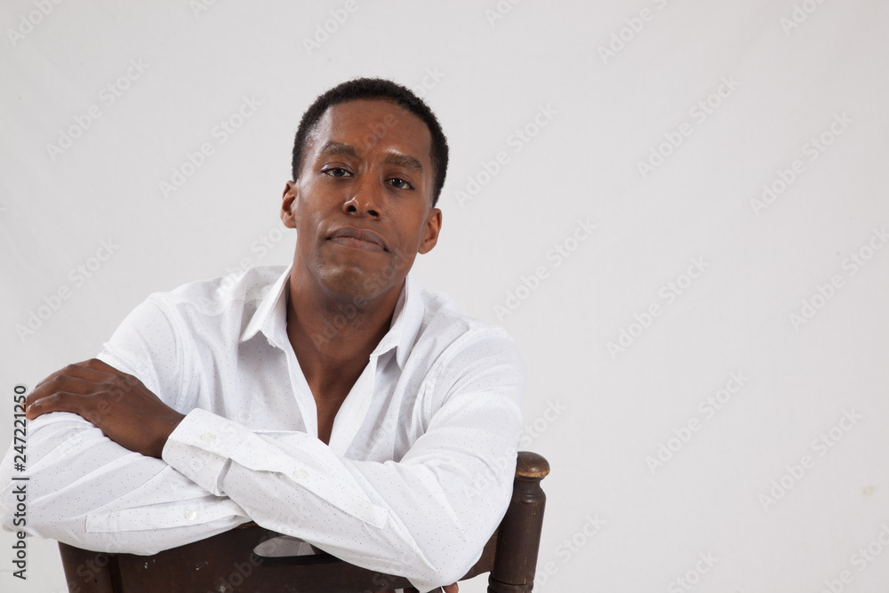 Black man in white shirt, sitting backwards in a chair Stock Photo | Adobe  Stock