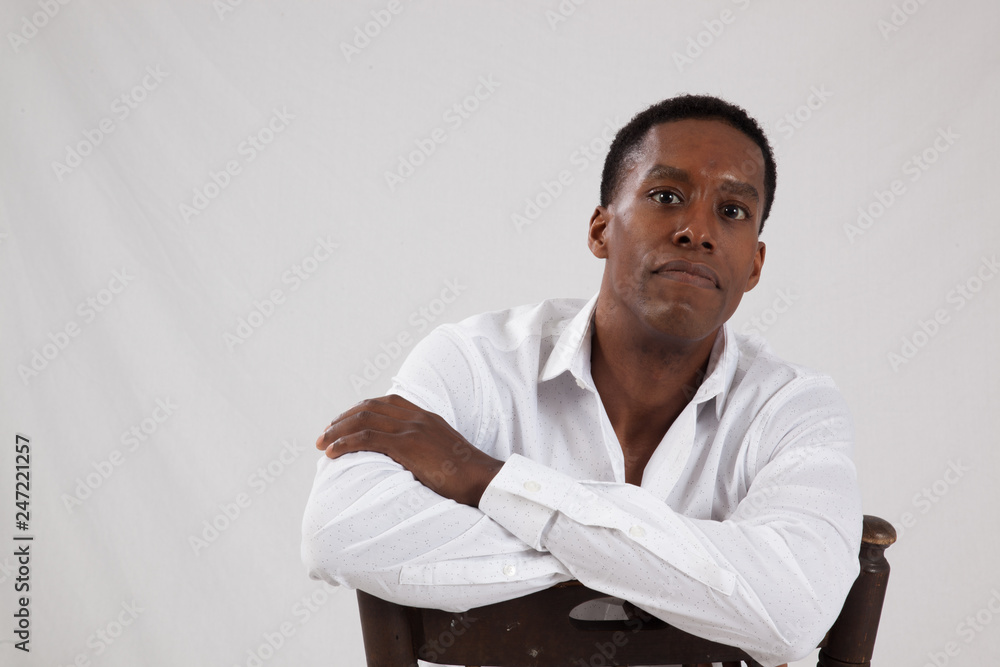 Black man in white shirt, sitting backwards in a chair Black man in white shirt, sitting backwards in a chair