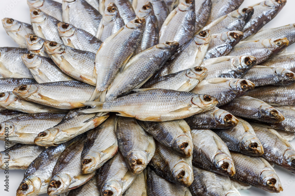 Large heap of dried salted sea roach laid out in the form of a circle on a white background. Close-up