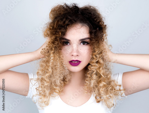 Young beautiful woman with freckles and curly hair studio portrait
