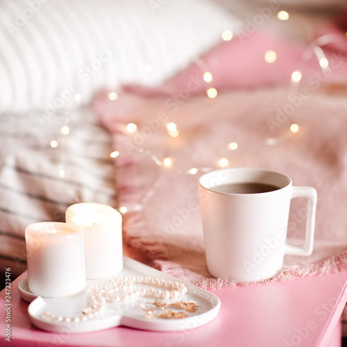 Cup of coffee with candles on white tray over lights at background. Good morning.