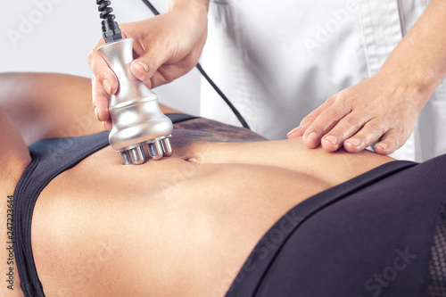 Schilderij op canvas The doctor does the Rf lifting procedure on the stomach and hips of a woman in a beauty parlor