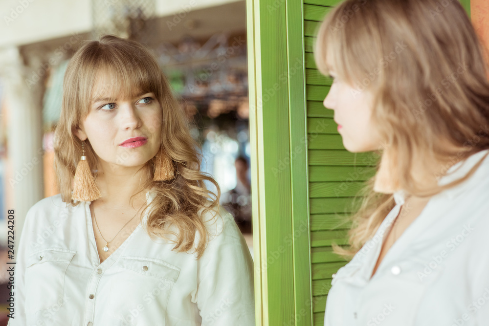 Young sad woman looking in the mirror at her wrinkles Young sad woman looking in the mirror at her wrinkles
