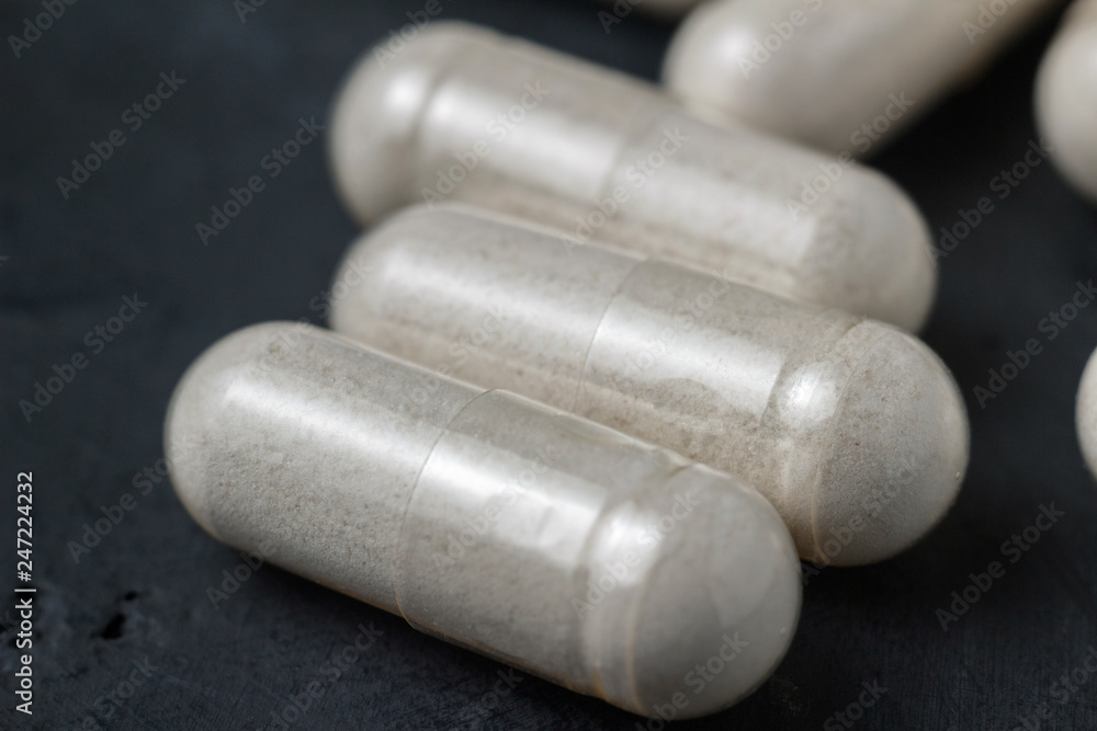 White medical capsules of glucosamine chondroitin, healthy supplement pills on a dark background, macro image White medical capsules of glucosamine chondroitin, healthy supplement pills on a dark background, macro image