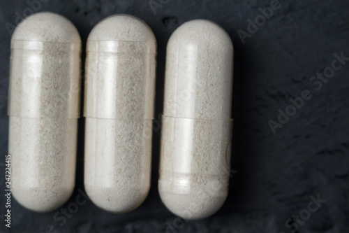 White medical capsules of glucosamine chondroitin, healthy supplement pills on a dark background, macro image photo