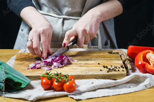 The chef cuts red onions on a wooden chopping Board. Background kitchen, side view