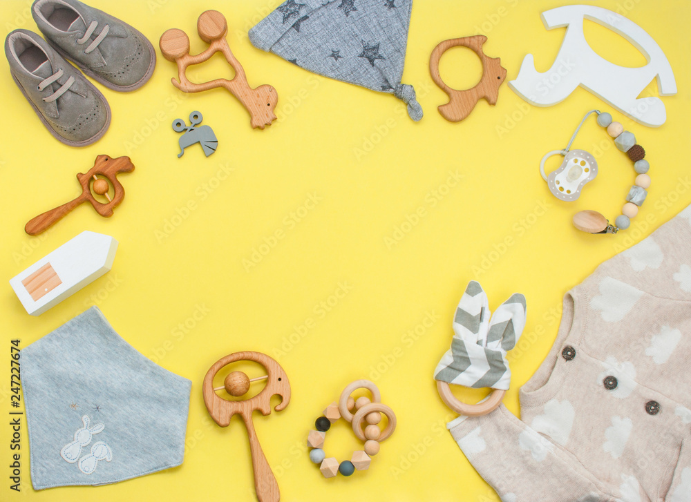 Frame of wooden toys, clothes and shoes on yellow background with copy space Frame of wooden toys, clothes and shoes on yellow background with copy space