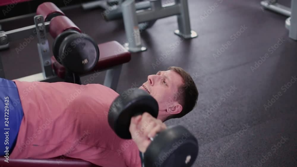 Athletic and attractive man doing dumbbell bench press in the gym. Athletic and attractive man doing dumbbell bench press in the gym.
