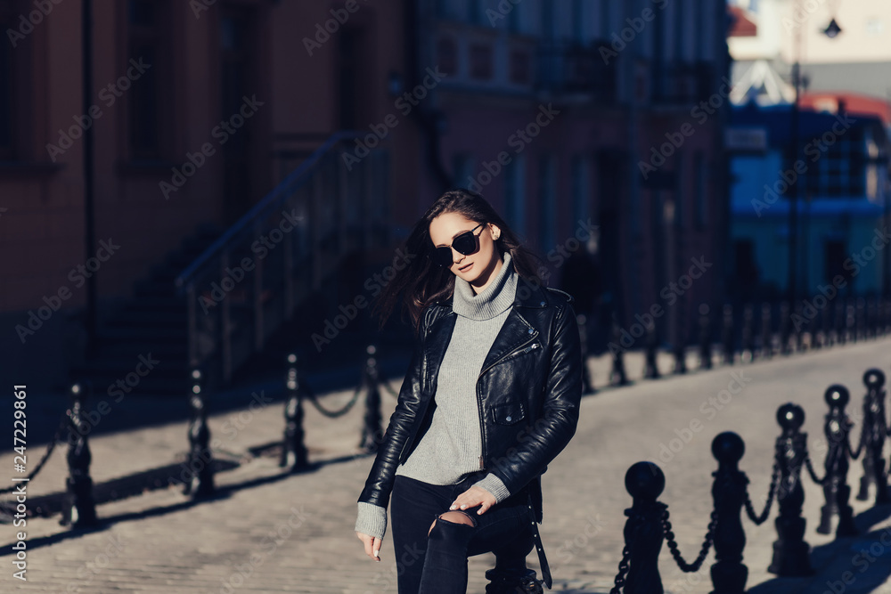 Obraz premium Happy woman in sunglasses and leather jacket walking outdoors