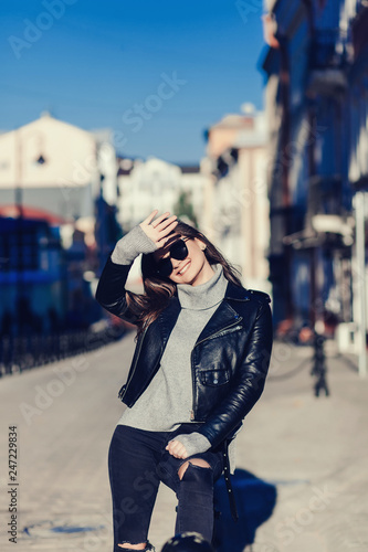 happy woman in sunglasses and leather jacket posing in the city © jozzeppe777
