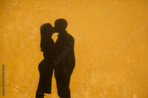 silhouettes of kissing people against a wall