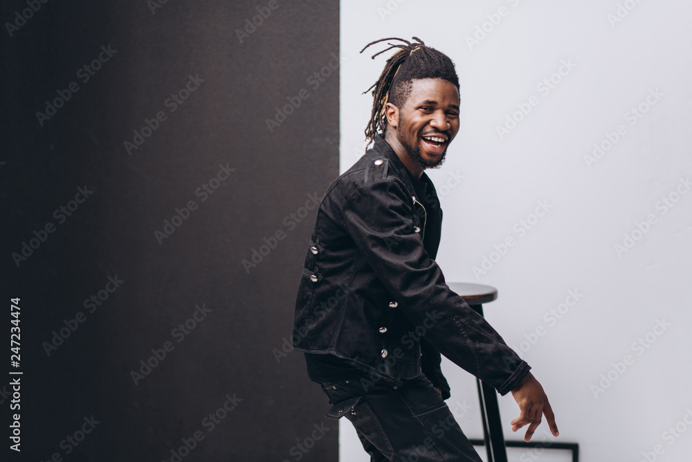 Fototapeta premium One attractive smiling black man in black jacket and black pants over gray background