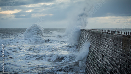 Stormy sea crashing over Tynemouth Pier, Tyneside, Engalnd, UK . In early morning light and sunrise.