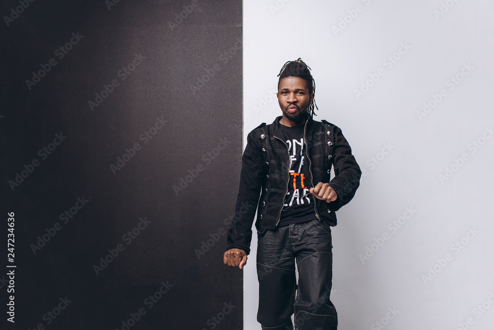 One attractive smiling black man in black jacket and black pants over gray background One attractive smiling black man in black jacket and black pants over gray background