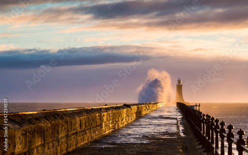 Stormy sea crashing over Tynemouth Pier, Tyneside, Engalnd, UK . In early morning light and sunrise.