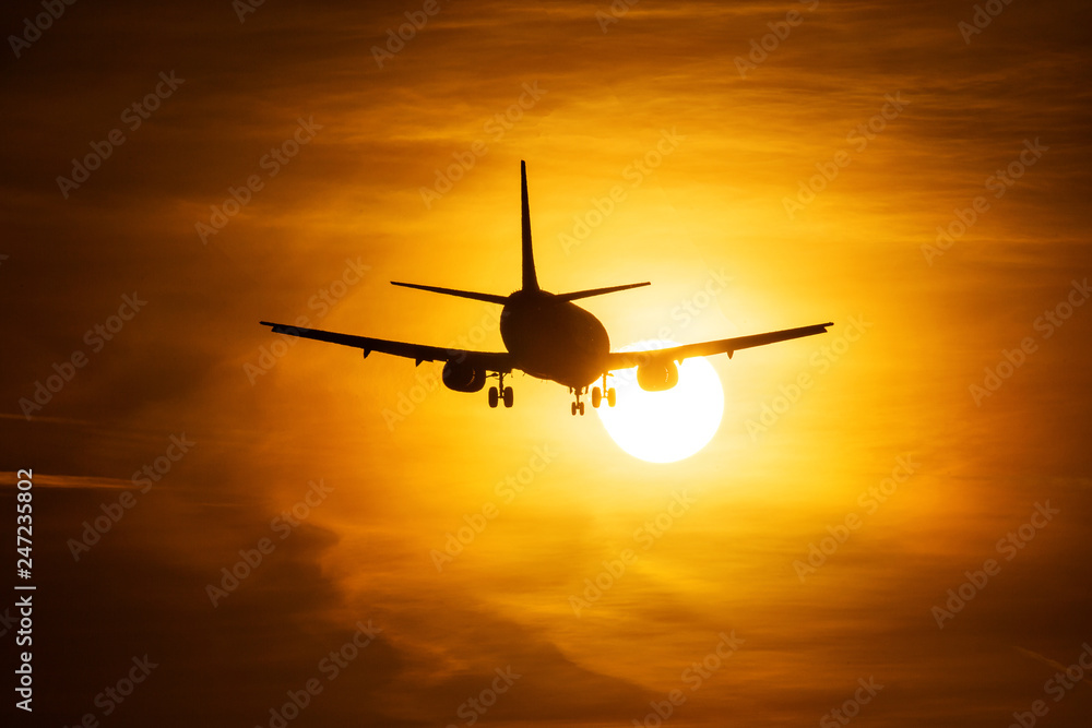 Silhouette of an air plane over the sun with beautiful red clouds in background Silhouette of an air plane over the sun with beautiful red clouds in background