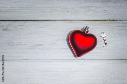 Red heart with key on white wooden background. Greeting card. Minimal Valentines day concept with copy space. Top view. Soft focus.