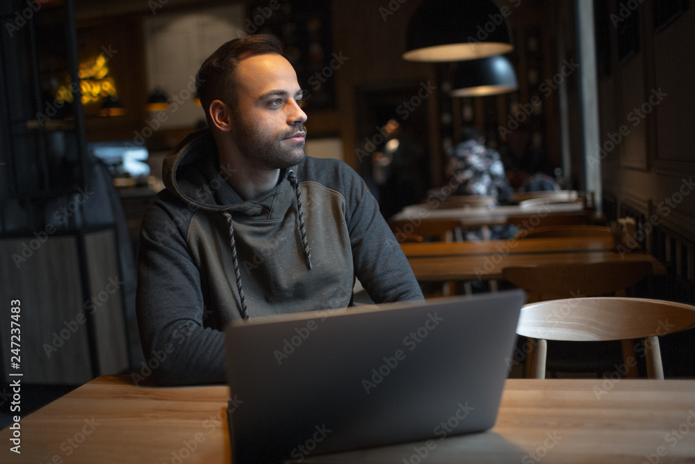 Young man working at laptop in cafe. Young man working at laptop in cafe.