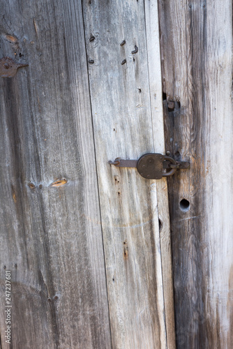 Rusty lock on the wooden doors. Lock on the door of an old farmhouse. Village style. Close-up. Wooden texture. Natural wood background.