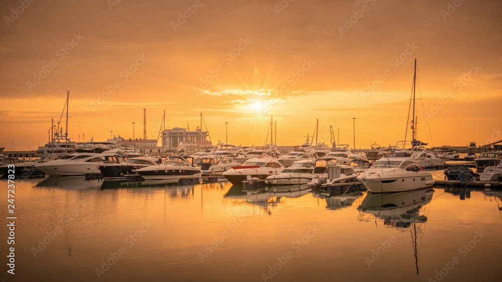 Beautiful orange sunset in the sea harbor with moored yachts.