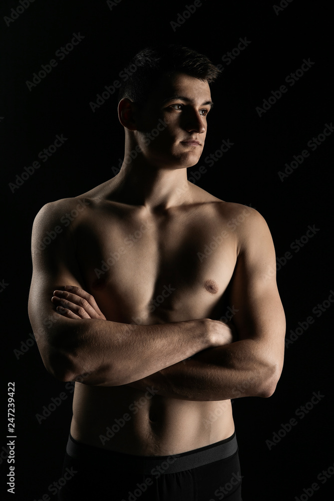 Fototapeta premium Portrait of a man with a beautiful athletic body in a low key. Pumped up guy with a naked torso.