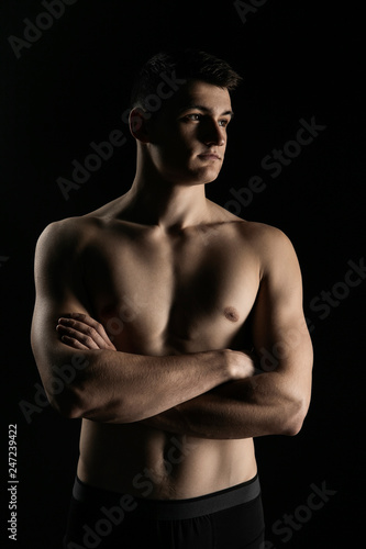 Portrait of a man with a beautiful athletic body in a low key. Pumped up guy with a naked torso. © slavonstok
