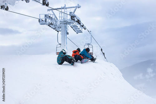 Snowboarder sitting and looking at mountain chain in the background.