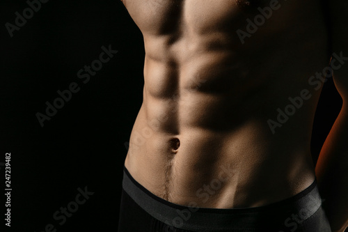 pumped handsome male press. Male athletic body closeup on black background