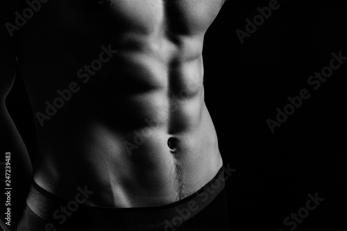 pumped handsome male press. Male athletic body closeup on black background photo