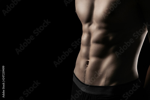 pumped handsome male press. Male athletic body closeup on black background