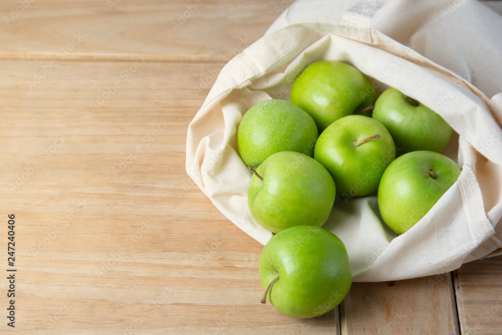 Bio fruit - green apples in white tote canvas fabric. Eco bag cloth shopping sack on wooden background . Zero waste concept. Copy space. Bio fruit - green apples in white tote canvas fabric. Eco bag cloth shopping sack on wooden background . Zero waste concept. Copy space.