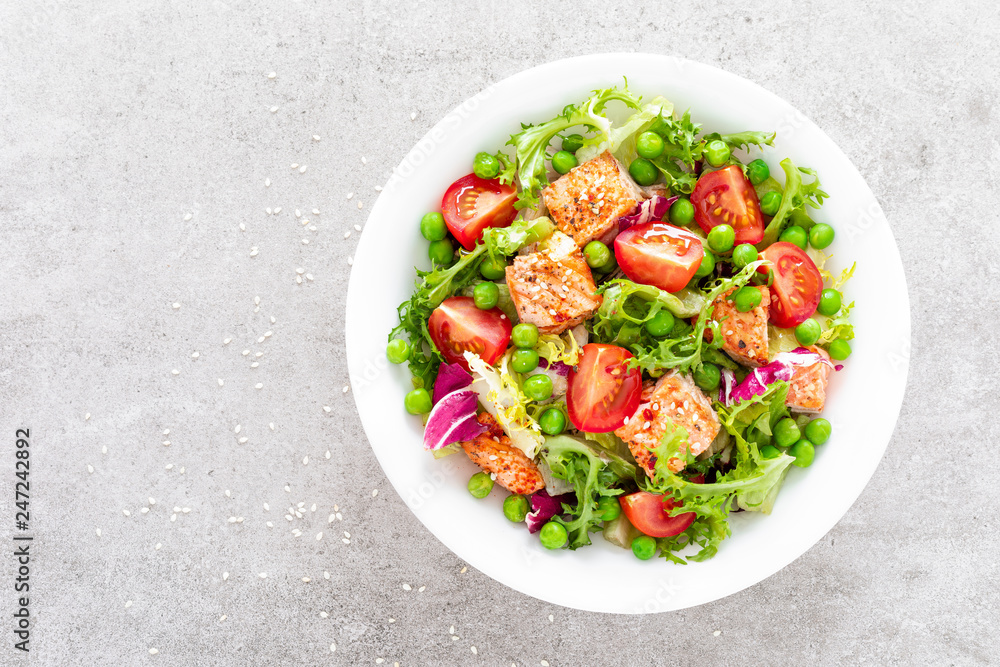 Healthy lunch vegetable salad with baked salmon fish, fresh green peas, lettuce and tomato. Top view Healthy lunch vegetable salad with baked salmon fish, fresh green peas, lettuce and tomato. Top view