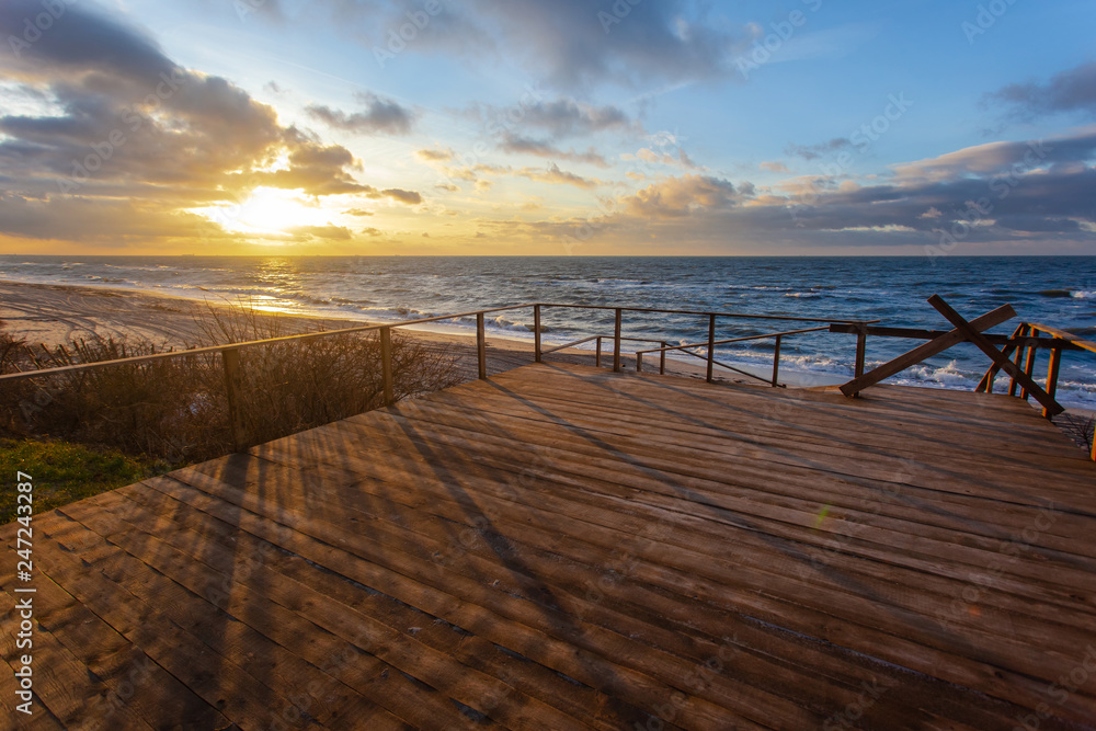 view of the colorful sunset over the sea from a wide wooden veranda