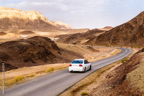 Car on road in sandstone desert landscape, Israel