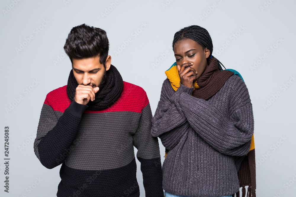 Sick couple, african woman and indian man in winter sneezing on white background Sick couple, african woman and indian man in winter sneezing on white background